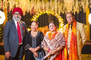 A group of adults in traditional attire at an elegant Indian wedding setting.