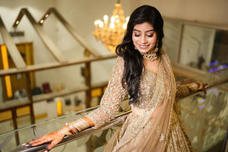 Beautiful Indian bride in shimmering lehenga and jewelry on a staircase, glowing with elegance.