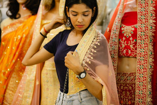 A young woman admires traditional saris in a vibrant Indian clothing store.