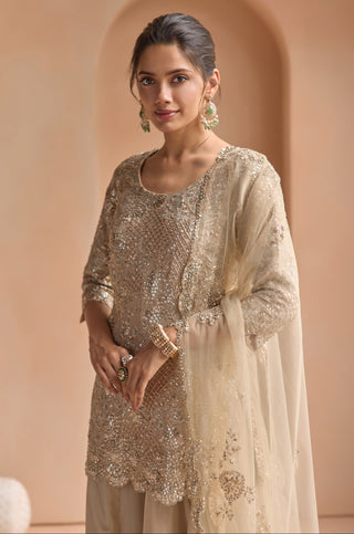 Waist-up view of champagne kurta with zardozi and sequin lattice and sheer ivory dupatta over one shoulder, at Mrs. G