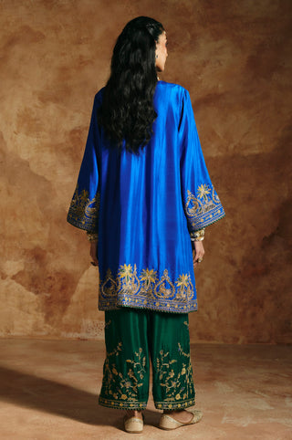 Back view of the cobalt blue kurta with embroidered cuffs and hem band over green pants by Aman Takyar at Mrs. G