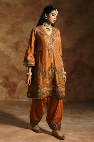 Three-quarter view of the rust kurta's flared embroidered cuffs and chest medallion by Aman Takyar at Mrs. G