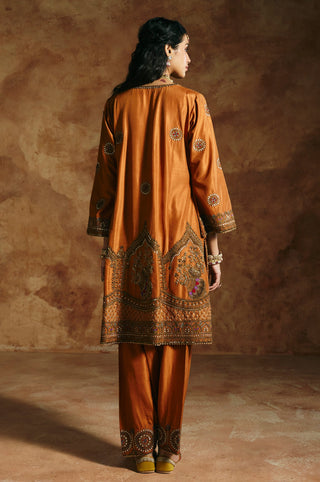 Back view of the rust kurta with its embroidered hem panel and round motifs by Aman Takyar at Mrs. G