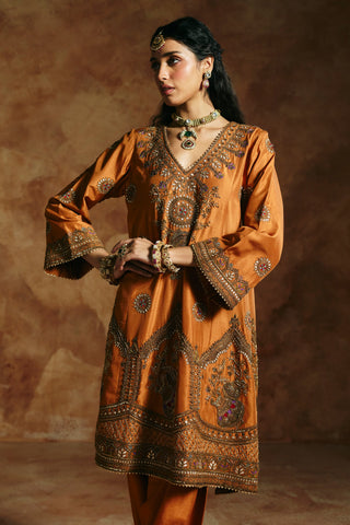 Side-glance view of the rust kurta's deep embroidered hem and flared sleeves by Aman Takyar at Mrs. G