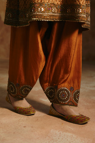 Close-up of the rust pants gathered at the ankle with round embroidered cuff medallions by Aman Takyar at Mrs. G