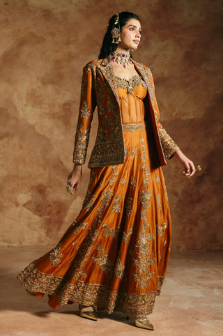 Walking view of the orange sharara flaring beneath the open gold-embroidered jacket by Aman Takyar at Mrs. G