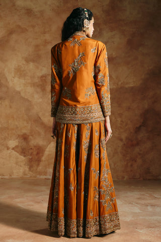 Back view of the orange jacket's gold floral embroidery and embroidered hem band by Aman Takyar at Mrs. G