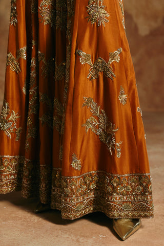 Close-up of the orange sharara's gold floral motifs and wide embroidered hem border by Aman Takyar at Mrs. G