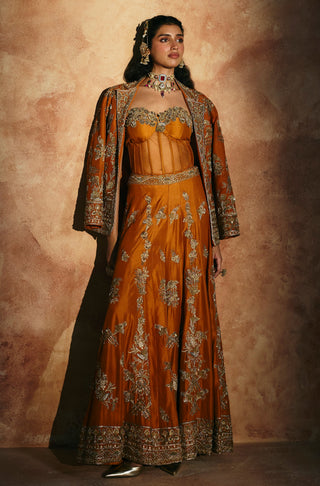 Full-length view of the orange jacket sharara set in a pool of light by Aman Takyar at Mrs. G