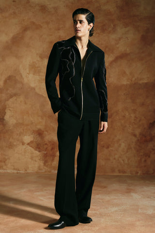 Three-quarter view of the black zipper jacket showing flowing beaded cord embroidery on the chest by Aman Takyar at Mrs. G