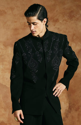 Full-length view of the black bandhgala set with hand on hip and beaded embroidery on the chest by Aman Takyar at Mrs. G