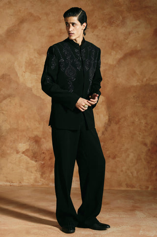 Three-quarter view of the black bandhgala set with beaded teardrop motifs across the shoulders by Aman Takyar at Mrs. G