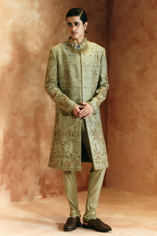 Full-length front view of the green sherwani set with embroidered hem and tonal pants by Aman Takyar at Mrs. G