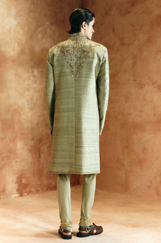 Back view of the green sherwani set turned to the side showing the upper back embroidery by Aman Takyar at Mrs. G