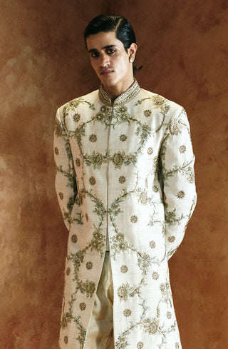 Front view of the ivory sherwani set with hands behind, showing the worked hem border by Aman Takyar at Mrs. G