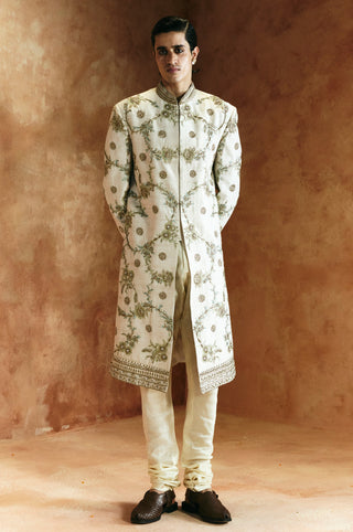 Full-length front view of the ivory sherwani set with a fitted churidar by Aman Takyar at Mrs. G
