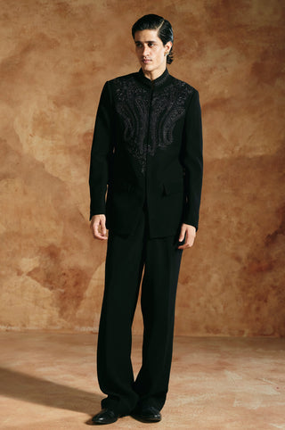 Front view of the black bandhgala set with paisley embroidery across the yoke by Aman Takyar at Mrs. G