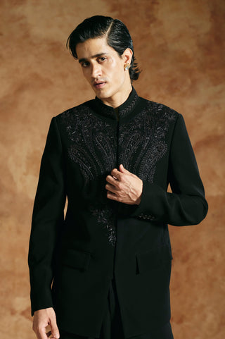 Waist-up view of the black bandhgala with one hand at the front and a flap pocket by Aman Takyar at Mrs. G