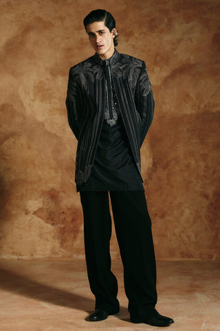 Front view of the black striped jacket, hands behind, with silver stripes from shoulder to hem by Aman Takyar at Mrs. G