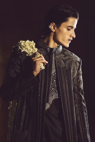 Side-turned waist-up view of the black striped jacket with a styled floral accessory by Aman Takyar at Mrs. G
