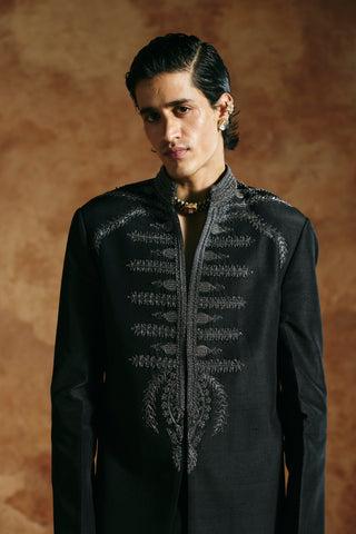 Waist-up close-up of the black long jacket with silver-gray zardozi and leaf sprigs by Aman Takyar at Mrs. G