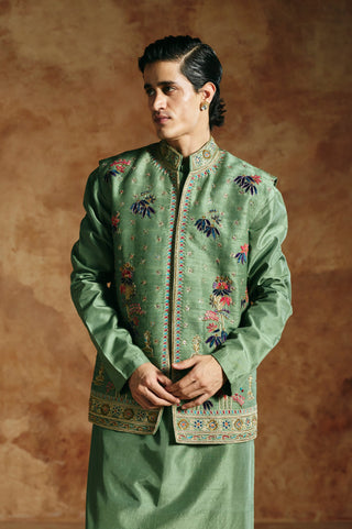 Waist-up view of the green nehru jacket with blue, pink and gold florals and a stand collar by Aman Takyar at Mrs. G