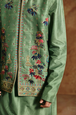 Close-up of the green nehru jacket with flowering plants, small birds and a bordered hem by Aman Takyar at Mrs. G