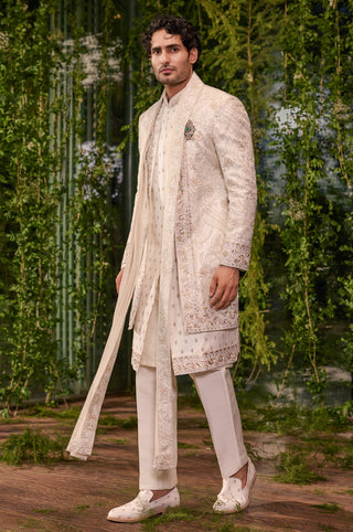 Side view of the ivory bespoke sherwani with long satin dupatta hanging from the shoulder by Jigar and Nikita at Mrs. G