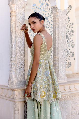 Side view of sage peplum top with a V back, zardozi embroidery and flared sequinned garara by Osaa by Adarsh at Mrs. G