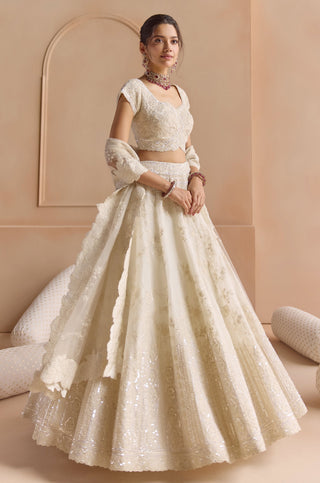 Three-quarter view of ivory lehenga set with cap sleeve blouse, tulle dupatta and sequin hem border by Osaa by Adarsh at Mrs. G
