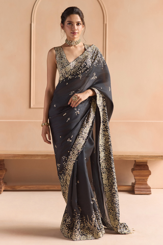Front view of black saree with gold sequin scatter and floral border over a sleeveless V-neck blouse by Osaa by Adarsh at Mrs. G