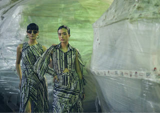 Two women in patterned outfits standing in front of a large bubble wrap structure.