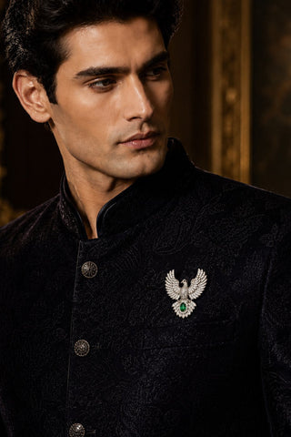 On-model view of the silver zircon bird brooch with green stone by Vivinia by Vidhi Mehra worn with a black sherwani at Mrs. G