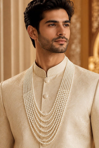 On-model view of the white multi-layer pearl groom mala by Vivinia by Vidhi Mehra worn with a cream sherwani at Mrs. G