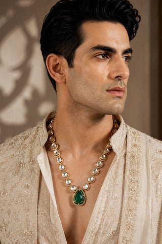 On-model view of the deep green kundan teardrop pendant necklace by Vivinia by Vidhi Mehra worn with a cream kurta at Mrs. G