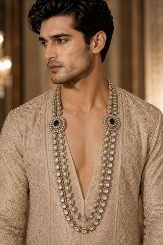 On-model view of the ivory double-layer kundan necklace with green centers by Vivinia by Vidhi Mehra worn with a beige embroidered sherwani at Mrs. G