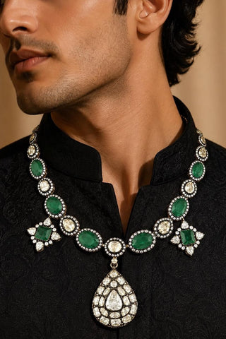 Close-up on model of the emerald green polki pendant necklace showing faceted green stones set in a dark metal finish at Mrs. G