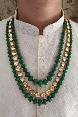 Close-up on model of the emerald green three-layer kundan beaded groom mala showing three strands at graduated lengths at Mrs. G