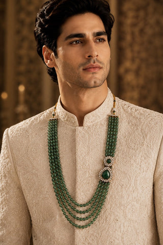 On-model view of the emerald green layered beaded statement groom mala by Vivinia by Vidhi Mehra worn with a cream sherwani at Mrs. G
