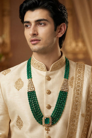 On-model view of the emerald green kundan beaded pendant groom necklace by Vivinia by Vidhi Mehra worn with a cream sherwani with gold border at Mrs. G