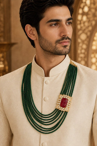 On-model view of the emerald green layered beaded groom mala with red stone motif by Vivinia by Vidhi Mehra worn with a cream bandhgala at Mrs. G