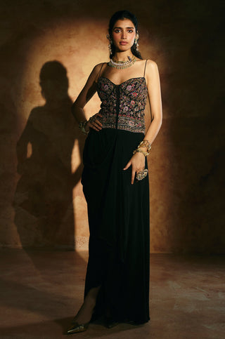 Front view of the black corset set with hand on hip and the skirt drape gathered at the hip by Aman Takyar at Mrs. G