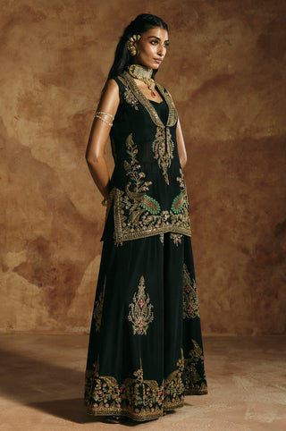 Three-quarter view of the black jacket sharara set with peacock motifs at the jacket hem by Aman Takyar at Mrs. G