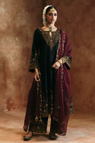 Full-length front view of the black keyhole kurta set with tasseled dupatta ends and embroidered pant hems by Aman Takyar at Mrs. G