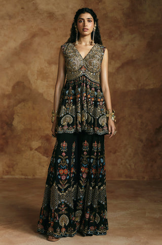 Full-length front view of the black peplum sharara set with gold-embroidered V-neck bodice by Aman Takyar at Mrs. G