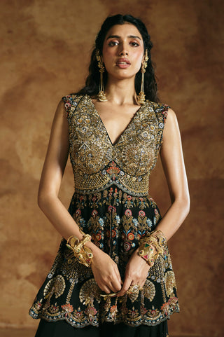 Waist-up view of the black peplum top's gold-worked V-neck bodice and scalloped embroidered hem by Aman Takyar at Mrs. G