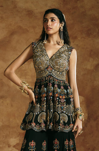 Full-length view with one hand on hip showing the black peplum top and wide sharara by Aman Takyar at Mrs. G