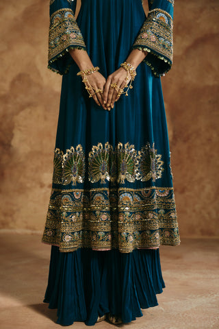 Close-up of the teal blue anarkali hem with gold peacock-fan motifs and bell sleeve cuffs by Aman Takyar at Mrs. G