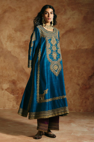 Three-quarter view of the teal blue kurta's flowing shape and side motif over plum pants by Aman Takyar at Mrs. G