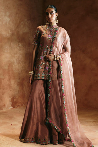 Full-length three-quarter view of the bronze sharara set with the dupatta draped across the arms by Aman Takyar at Mrs. G